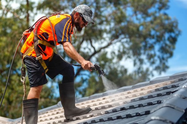Canberra roofing contractors painting and restoring a residential roof for a fresh and durable finish.
